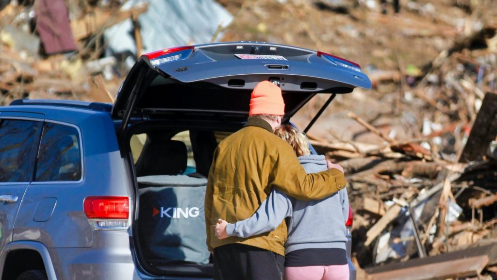 A couple surveys tornado damage knowing they face hardship recovery