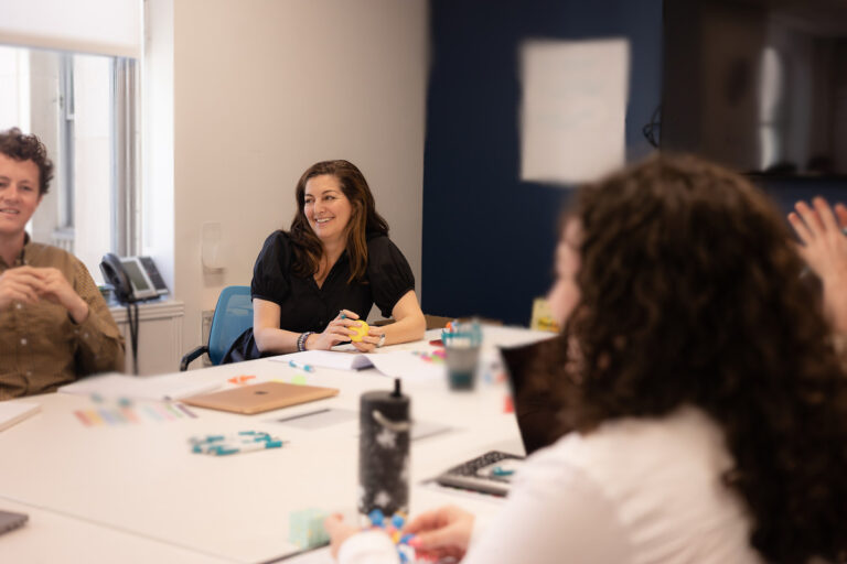 Rachel Schneider, founder and CEO of Canary, sits at a conference room table in a meeting with Canary employees