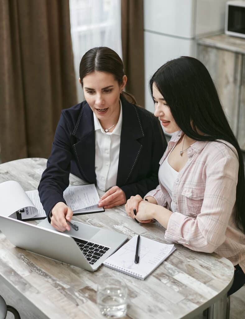 Two office workers looking at a laptop